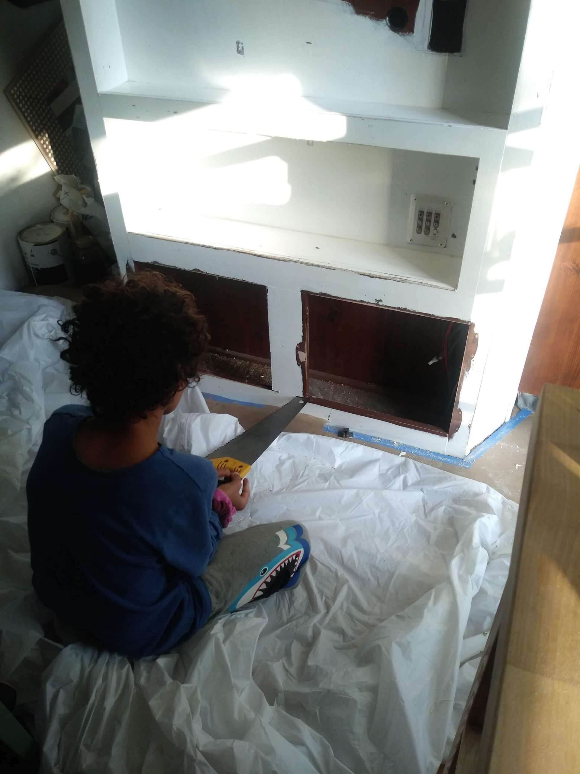 Young child using hammer to smash cabinet in RV renovation