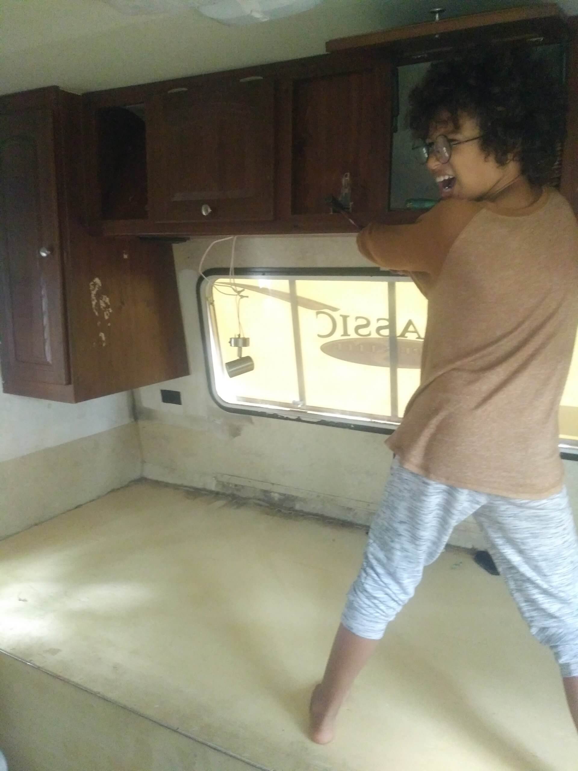 Young child using hammer to smash cabinet in RV renovation